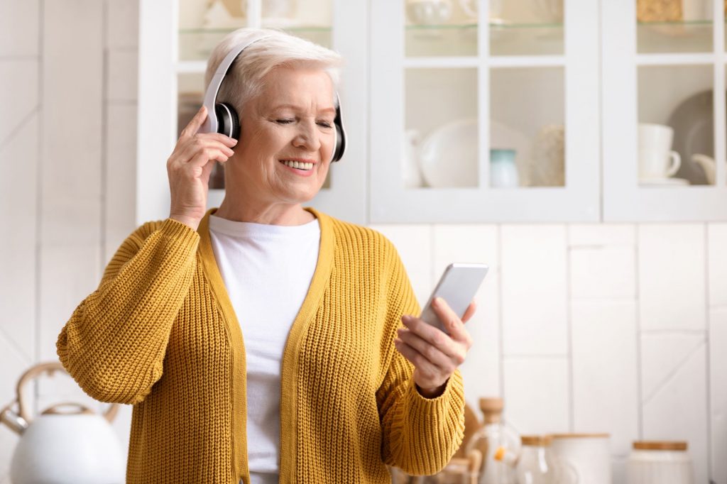 Senior woman smiling and listening to podcasts for boomers