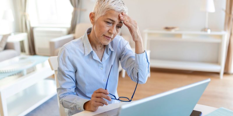 senior woman sitting at a computer looking stressed