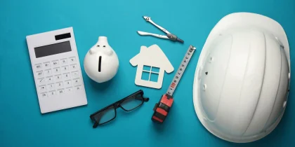 Engineer's tools and piggy bank, house model on blue background. Construction budget