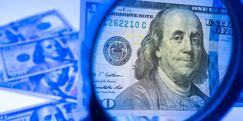 magnifying glass looking at a hundred dollar bill with UV light