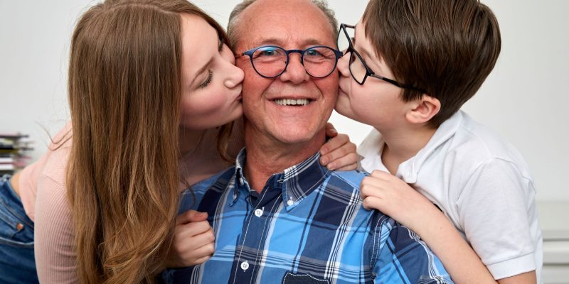older parent or grandparent being kissed by kids on the cheek