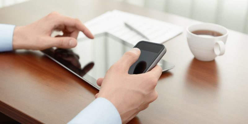phone and tablet on table with cup of coffee