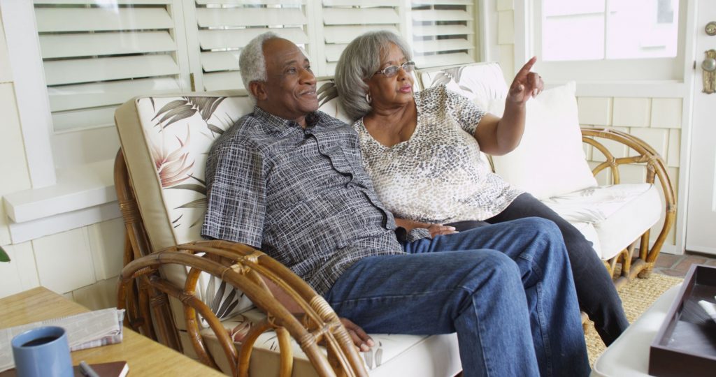 elderly African-American couple sitting on the front porch of their home