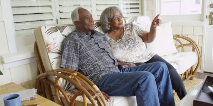 elderly African-American couple sitting on the front porch of their home