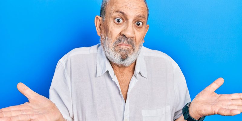 shrugging senior man with blue blackground