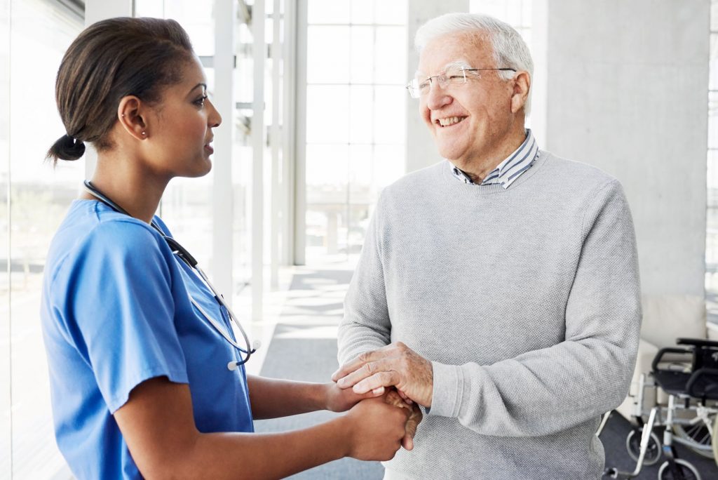 older gentleman with younger nurse in hallway of nursing home
