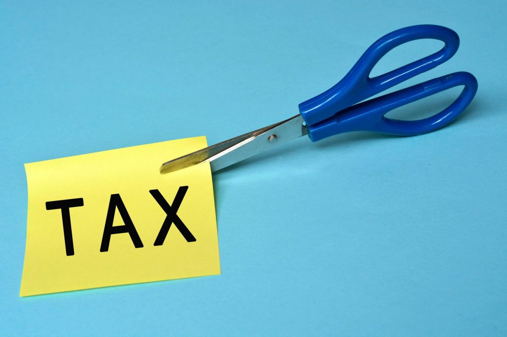 word tax written on paper and being cut by a pair of scissors, property tax cutting
