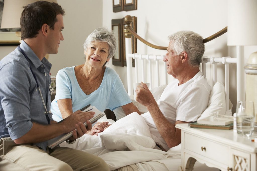 home care provider with husband and wife at bedside