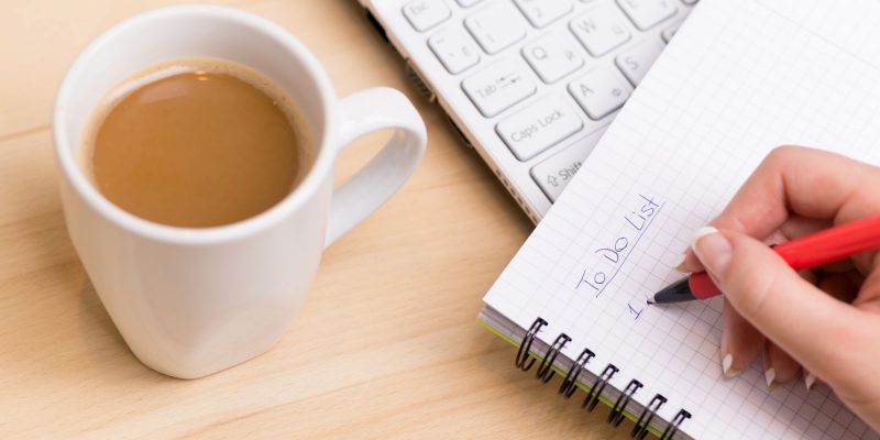 to-do check list with a cup of coffee sitting by a computer