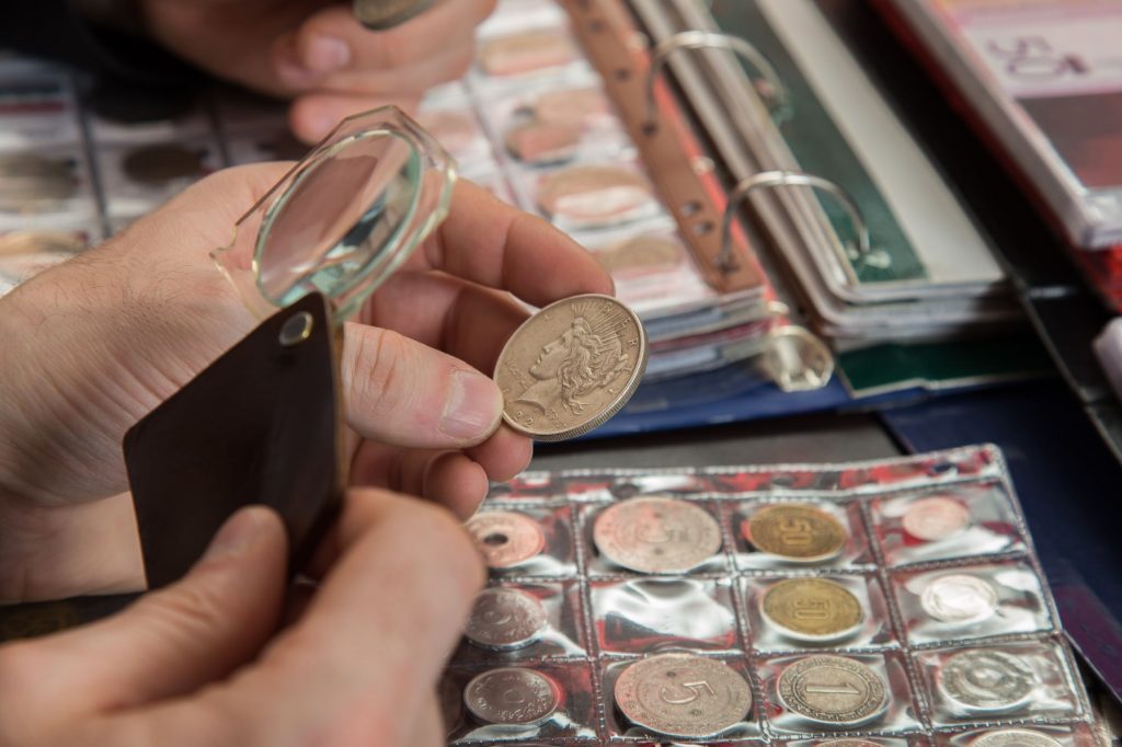 A hand examining an old, burnished coin.