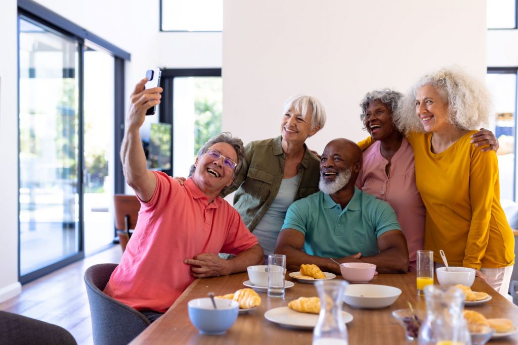 group of Baby Boomer firneds taking a selfie at a table