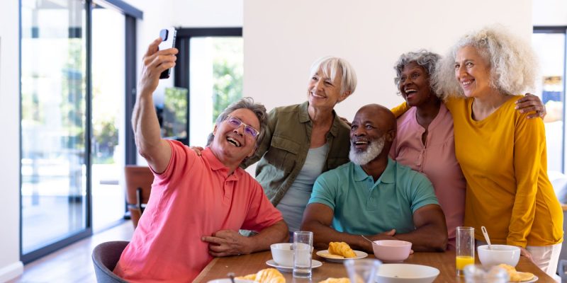 group of Baby Boomer firneds taking a selfie at a table