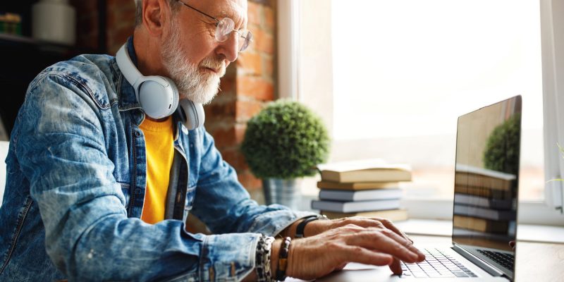man in jean jacket on a computer