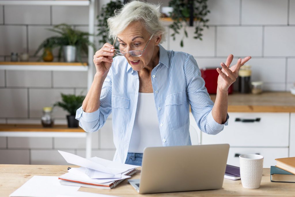 elderly woman standing in front of a computer surprised about RMDs