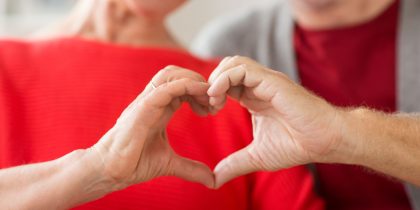 Two grandparents joining their hands together in a heart shape signifying their love for their grandchildren.