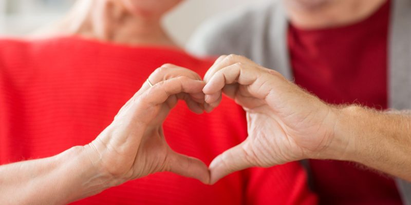 Two grandparents joining their hands together in a heart shape signifying their love for their grandchildren.