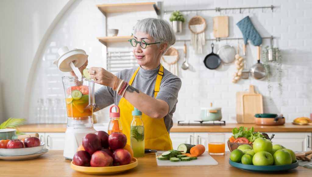 Asain lady with yellow apron making a smoothie