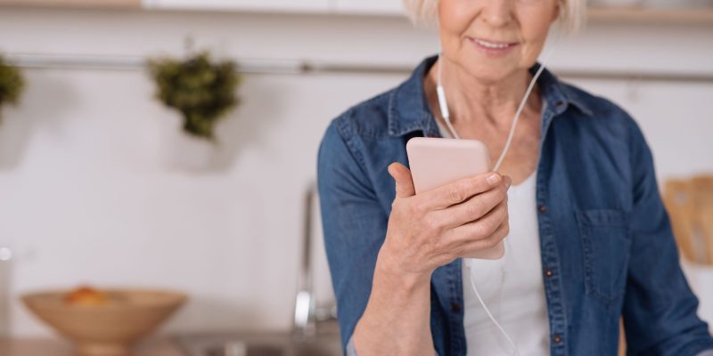 senior woman listening to a podcast with earbuds