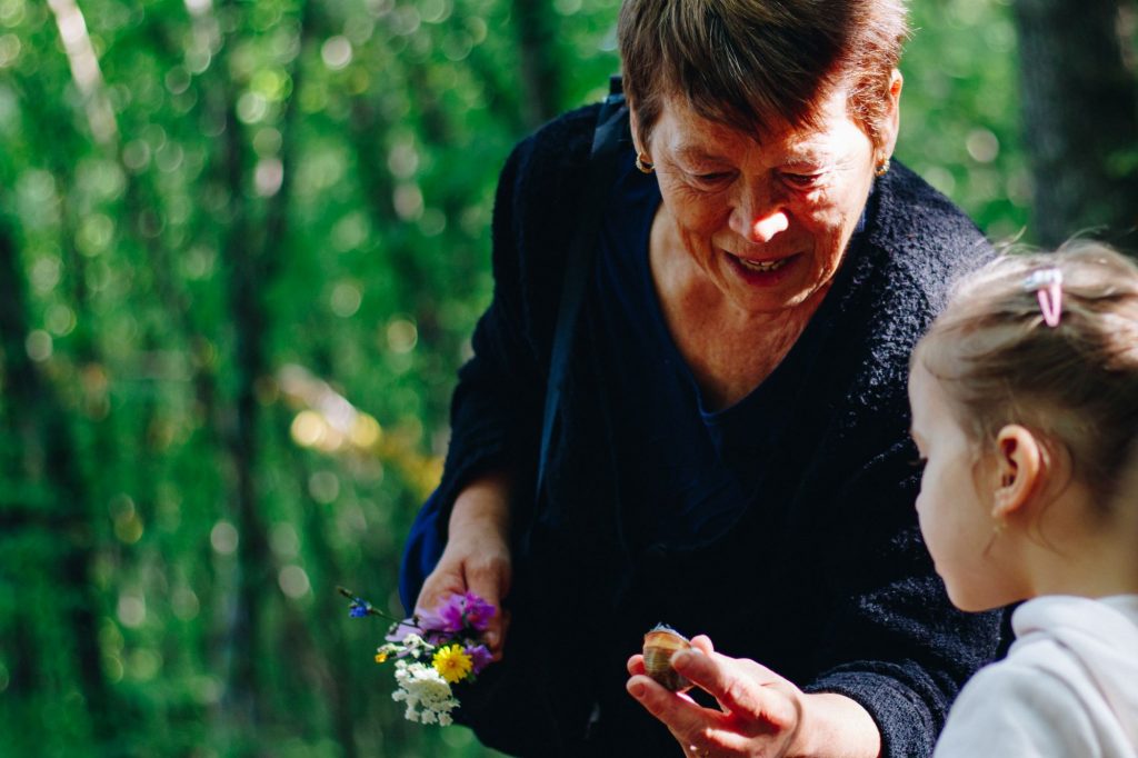 Grandmother out on a walk and picking flowers with her grandkids.