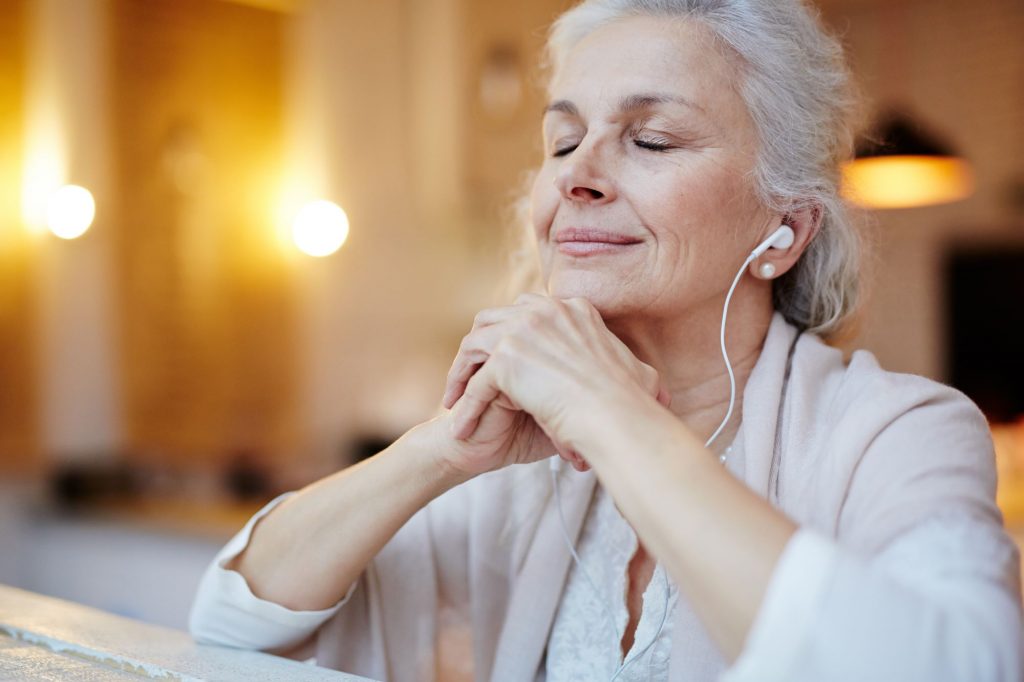 senior woman listening to earbuds, blurred background