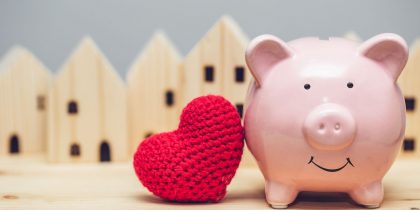 piggy bank with heart and houses in background