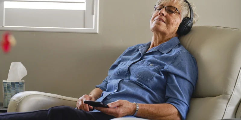 senior woman sitting in a recliner wearing headphones