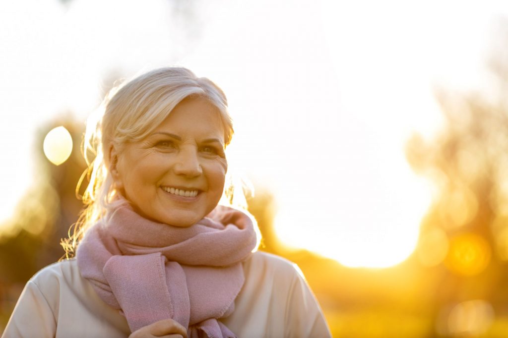 Older smiling woman amid a background of bokeh and light.