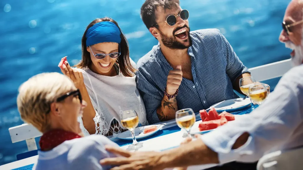 Baby Boomers and younger couple socializing on a cruise ship and having a meal together on the deck