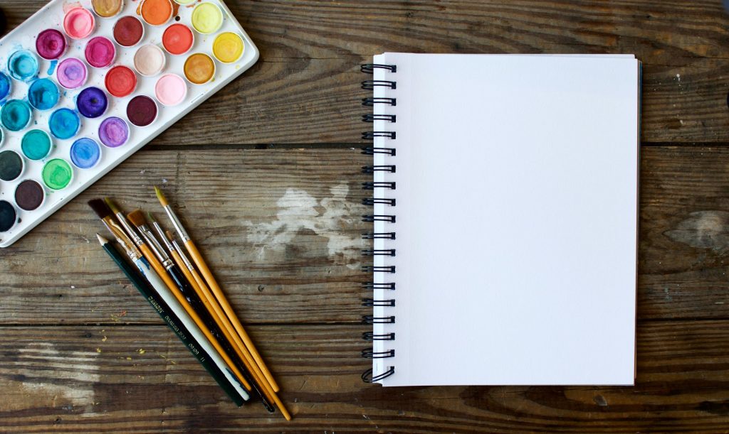 art supplies sitting on a wood surface next to blank paper