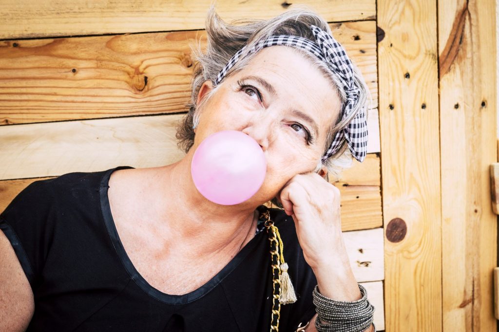 senior woman blowing a bubble with gum