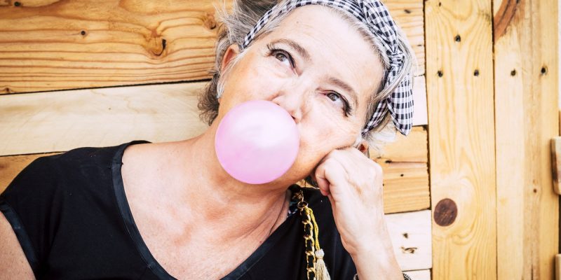 senior woman blowing a bubble with gum