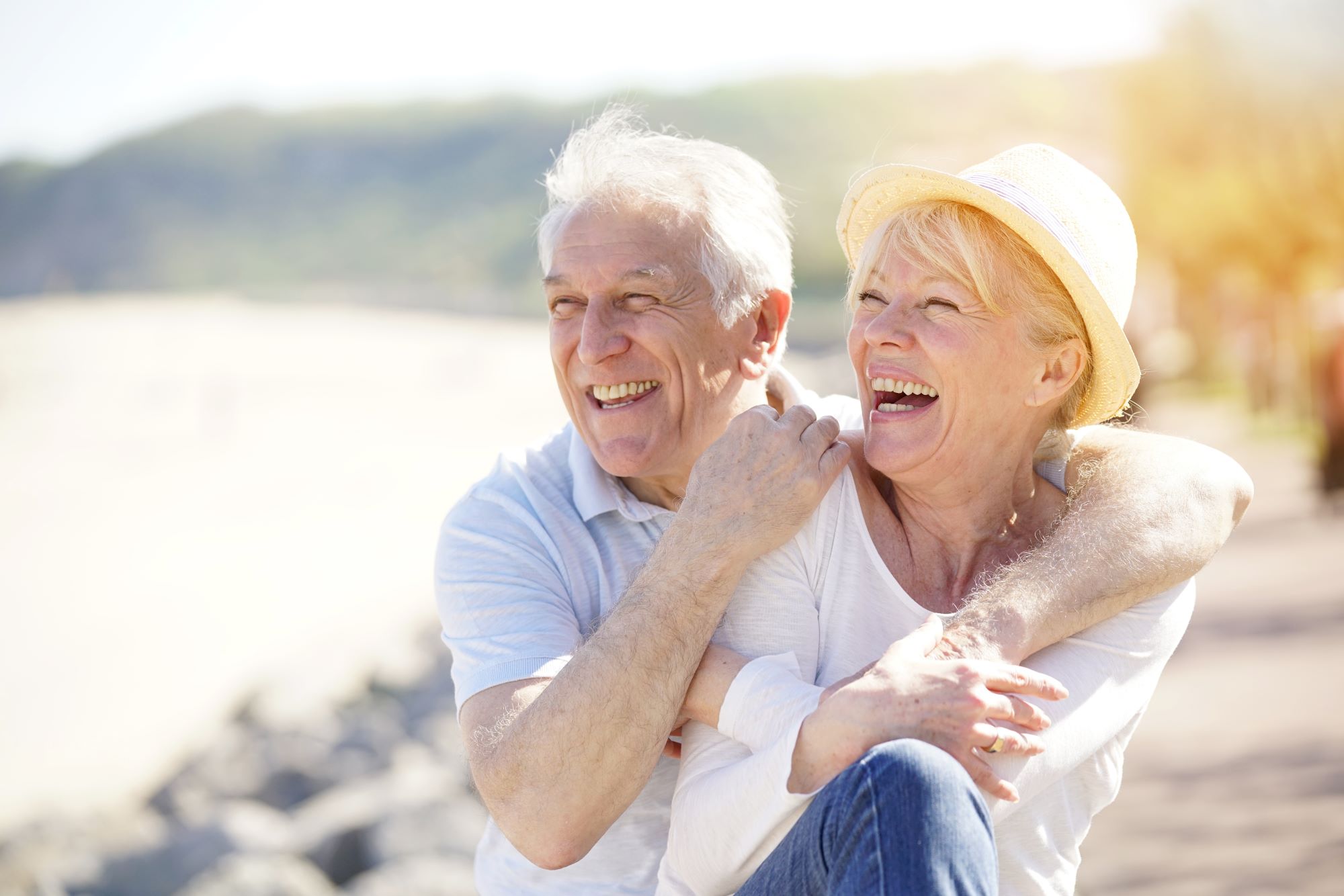 two seniors sitting on the beach smiling