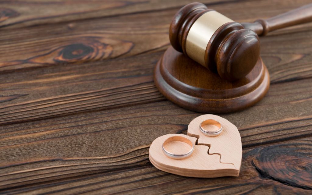 gavel and two wedding rings on a broken heart to symbolize divorce