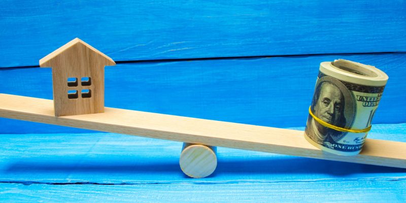 house and wrapped up money on a teeter totter