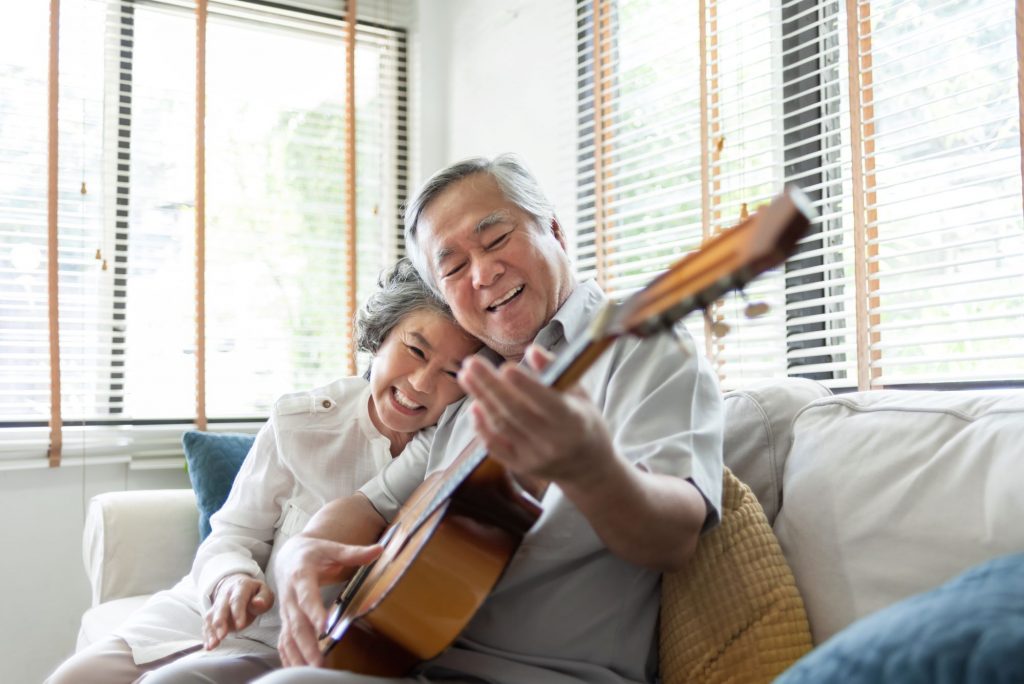 Asain senior couple playing guitar and smiling in an active adult community