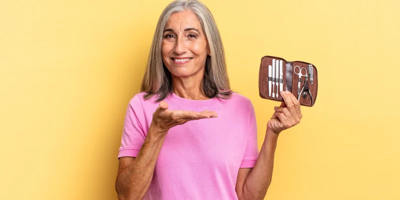 smiling cheerfully, feeling happy and showing a concept in copy space with palm of hand holding a nails tools case
