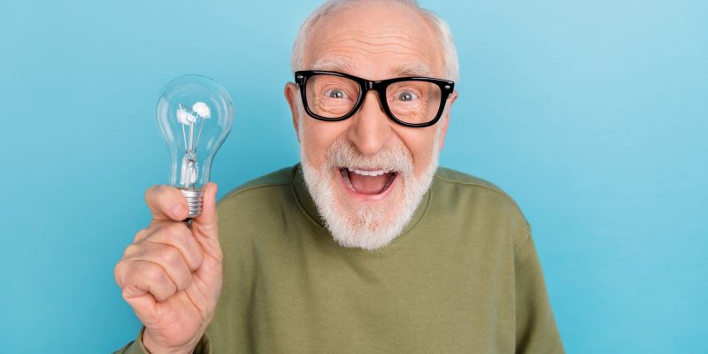 senior man holding a lightbulb with a bright idea