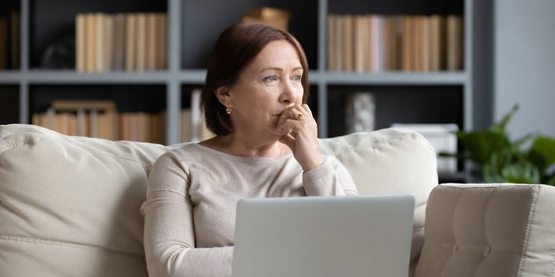 pensive senior woman using computer on the couch