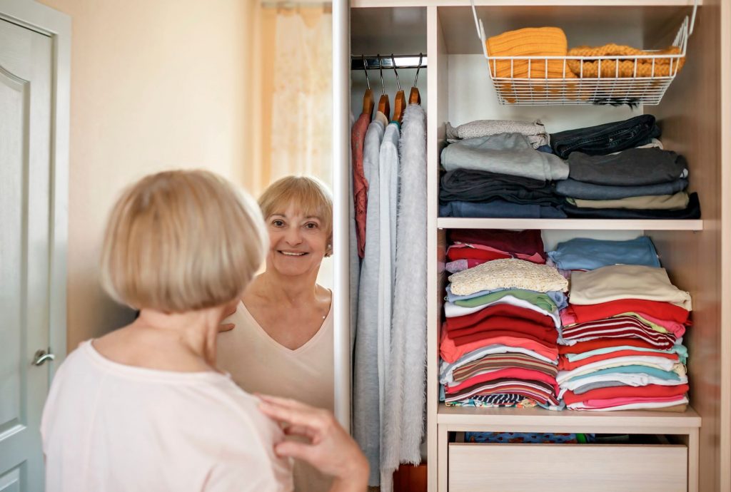 senior woman over 50, 55, 65, looking through her closet for clothing
