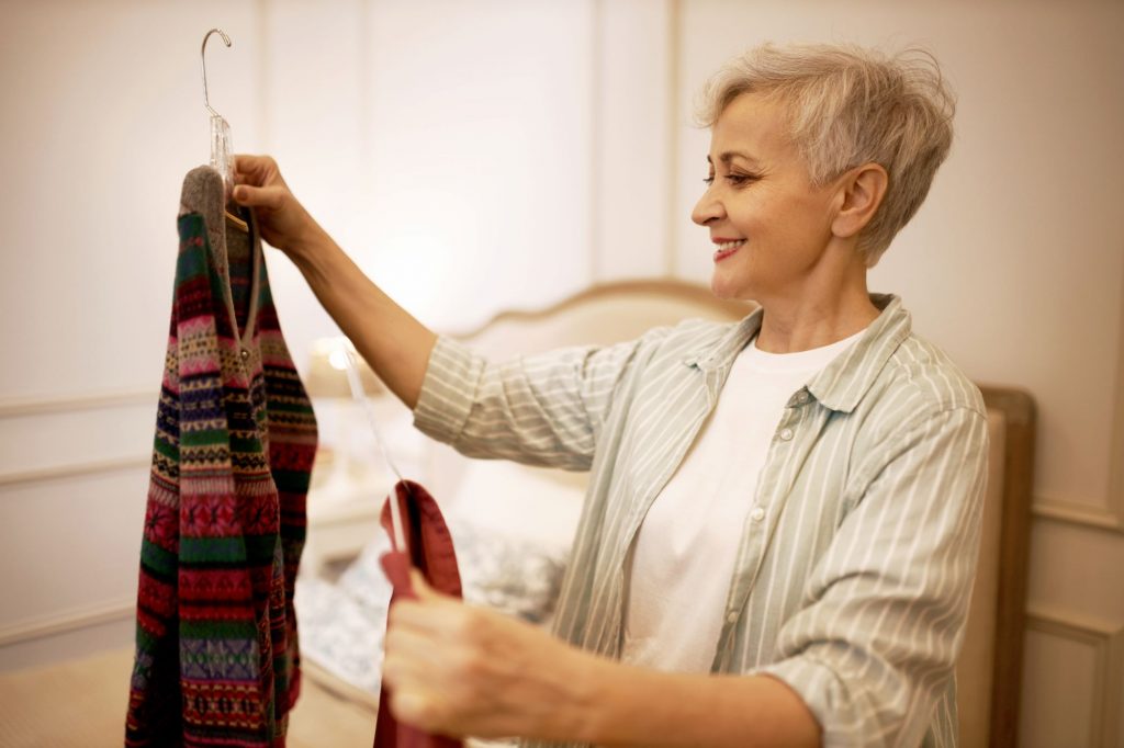 50 year old woman looking at clothes in her closet