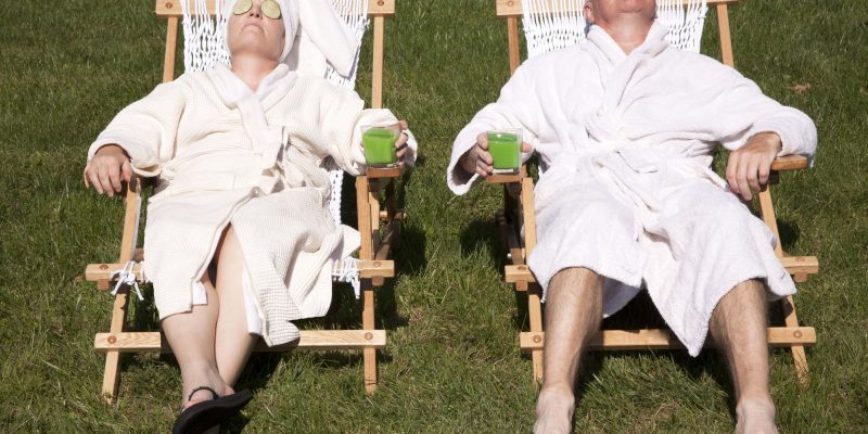 two retirees lounding in bathrobes with cucumbers on their eyes