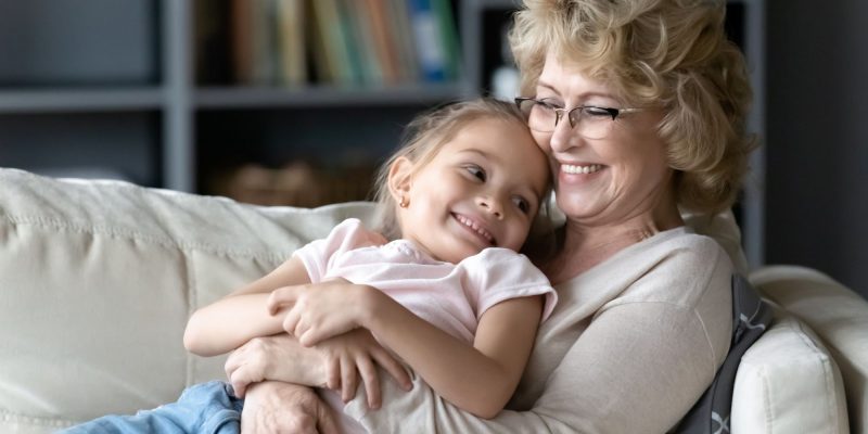 grandmother holding granddaughter on the couch