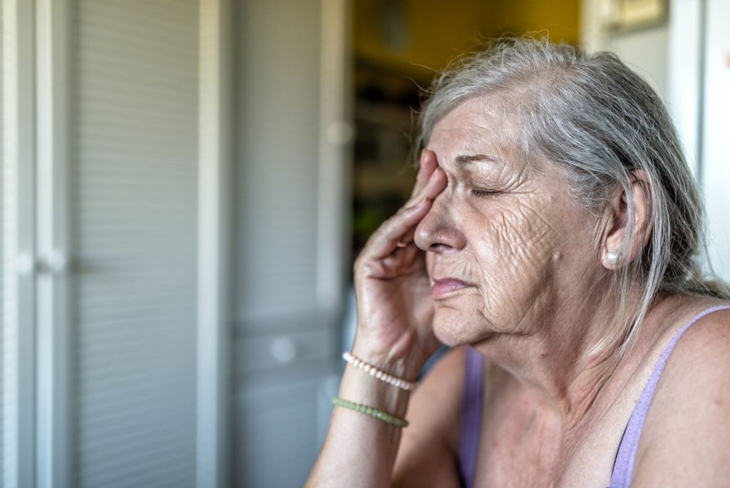 senior woman with hand over eye, sad or in pain