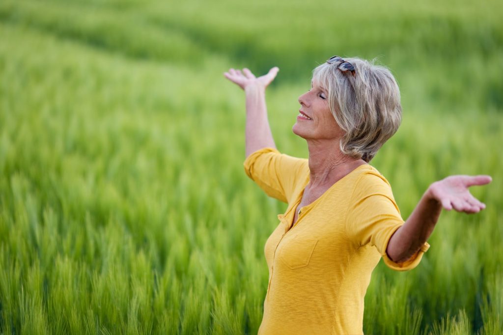 senior/retired woman outside with arms raised
