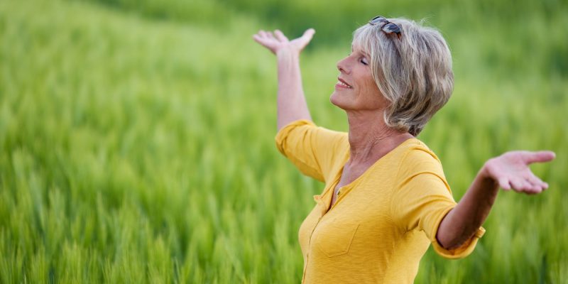 senior/retired woman outside with arms raised
