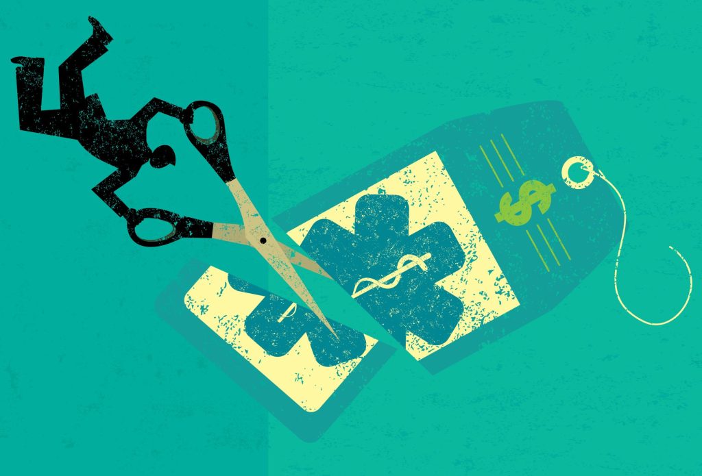 Cutting Health Care Costs A businessman cutting the high price of healthcare tag with large scissors over an abstract background.
