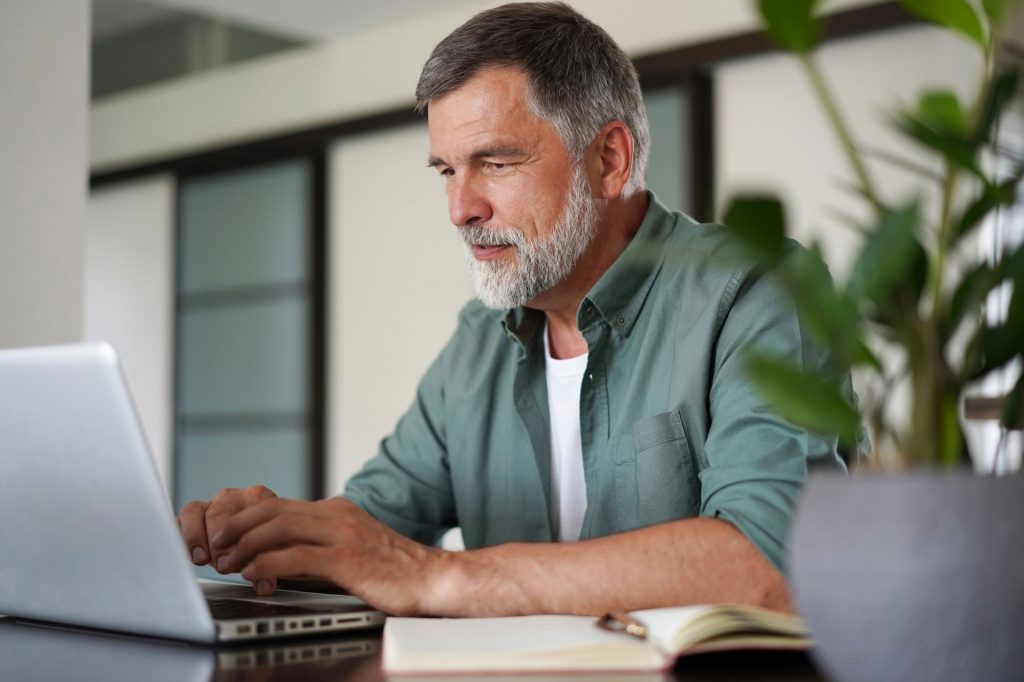 older adult man with a beard using a computer