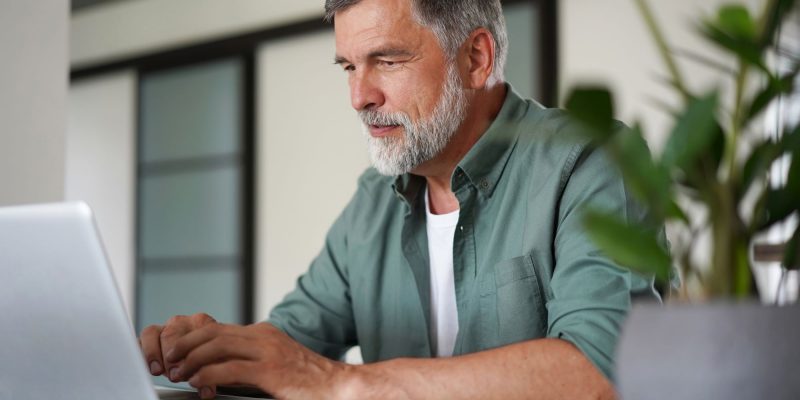 older adult man with a beard using a computer