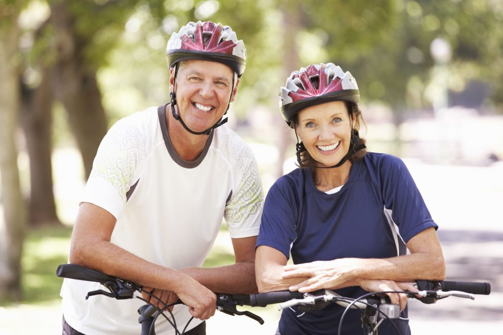two senior adults over 55 wearing bike helmets and smiling