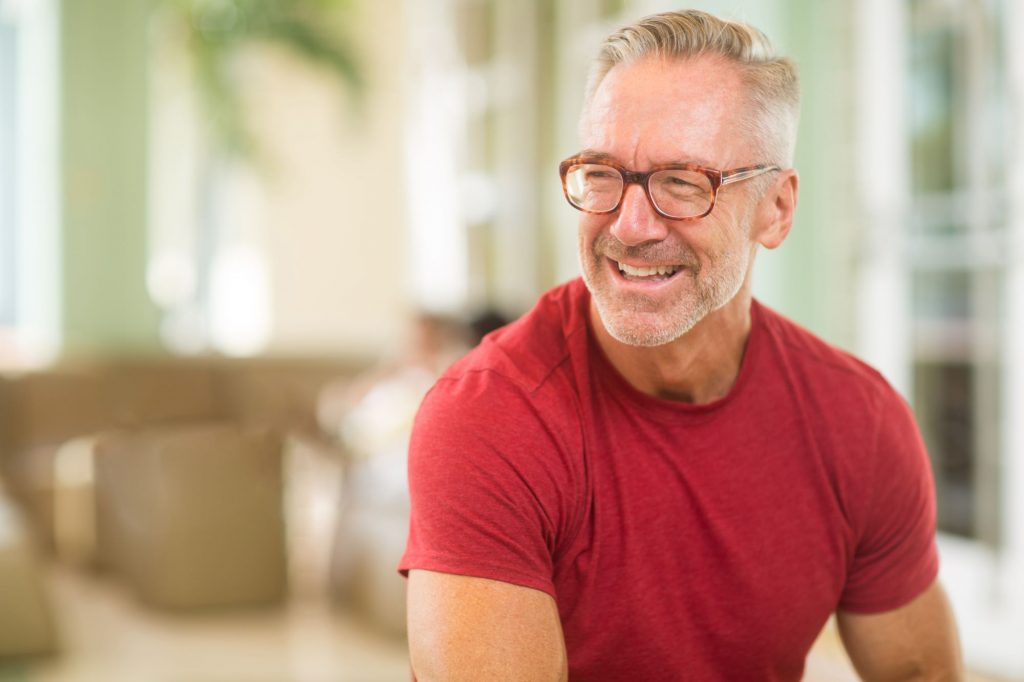 happy older adult man with glasses and red shirt